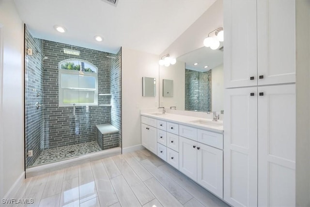 full bathroom featuring a sink, baseboards, double vanity, and a shower stall