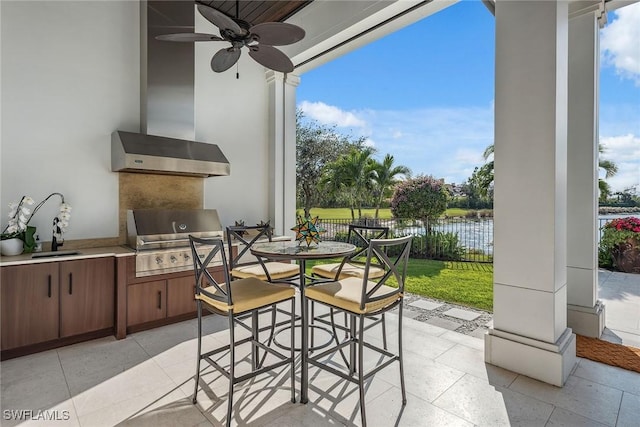 view of patio featuring ceiling fan, sink, exterior kitchen, a grill, and a water view