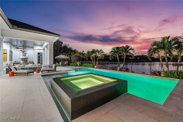 pool at dusk with outdoor lounge area, an in ground hot tub, and a patio