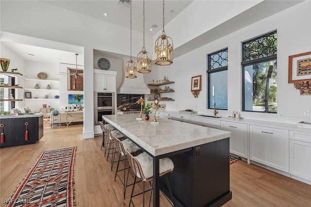 kitchen with decorative light fixtures, a center island, a kitchen bar, and white cabinetry