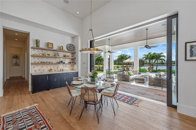 dining area featuring hardwood / wood-style floors, ceiling fan, and a high ceiling