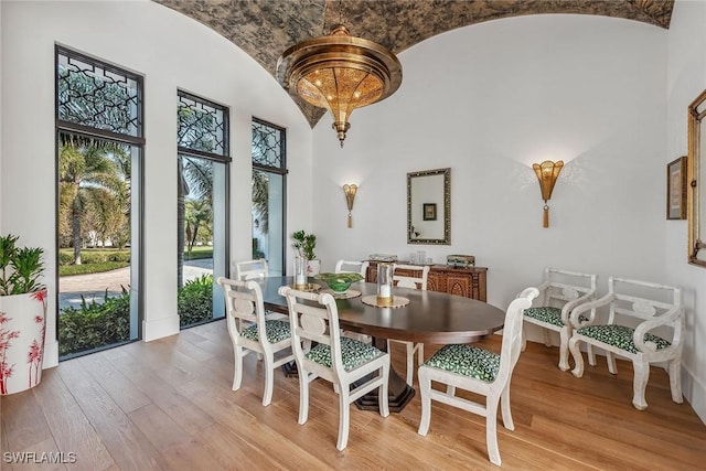 dining room with light hardwood / wood-style floors, plenty of natural light, lofted ceiling, and brick ceiling