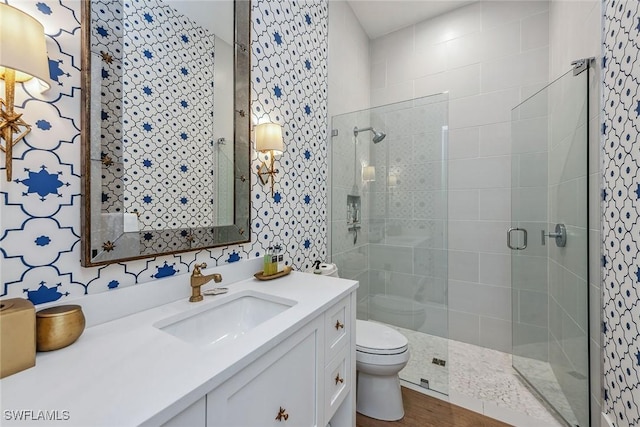 bathroom with hardwood / wood-style flooring, vanity, a shower with shower door, and toilet