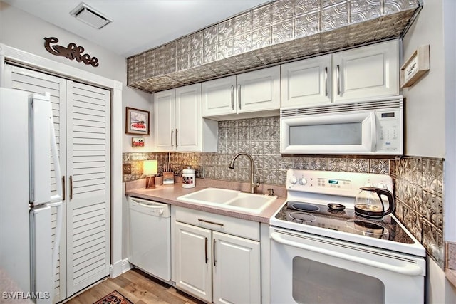 kitchen with white cabinetry, sink, backsplash, white appliances, and light wood-type flooring