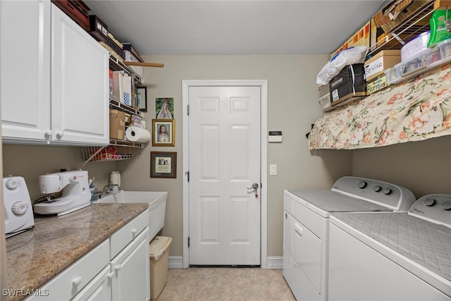 laundry area featuring washing machine and clothes dryer, light tile patterned floors, and cabinets