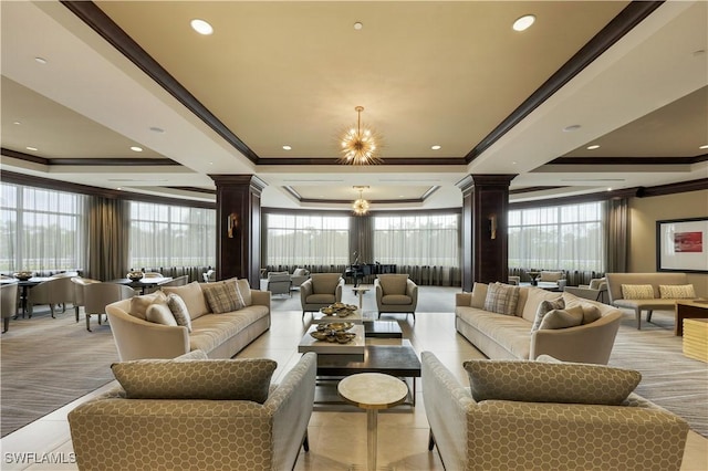 living room with ornate columns, a raised ceiling, crown molding, and a chandelier