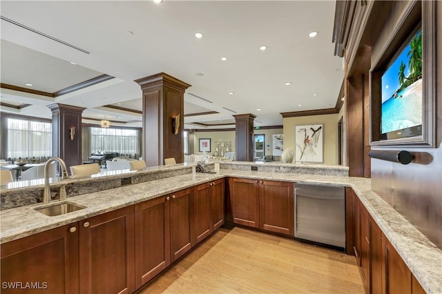 kitchen with ornate columns, crown molding, light stone countertops, and sink