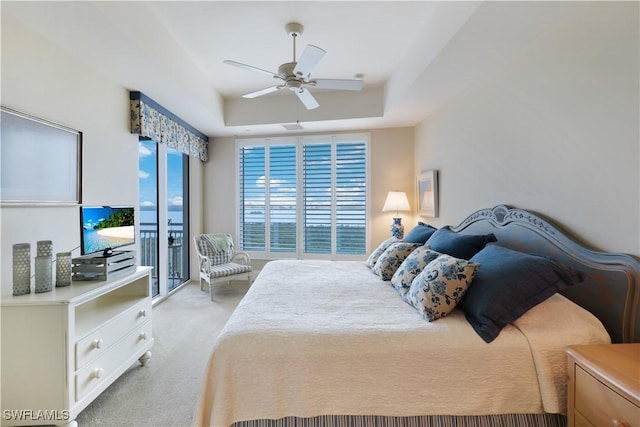 carpeted bedroom featuring ceiling fan and a raised ceiling