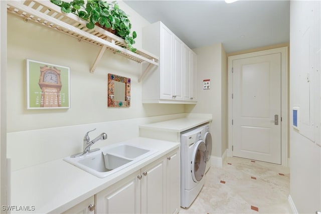 clothes washing area featuring cabinets, washing machine and dryer, and sink