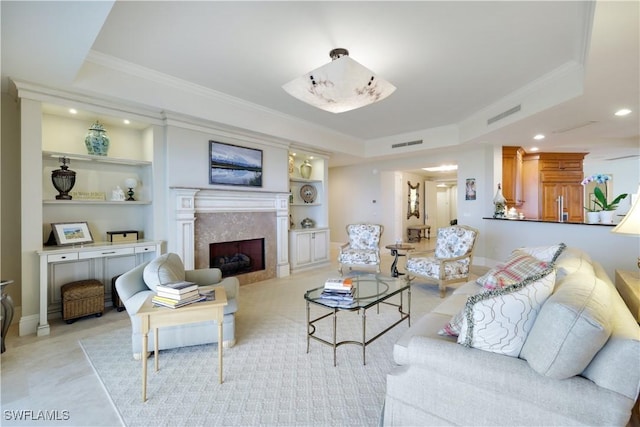 living room with built in shelves, ornamental molding, and a tray ceiling