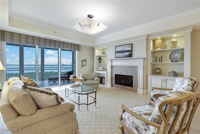 living room featuring a premium fireplace, a water view, crown molding, and built in shelves