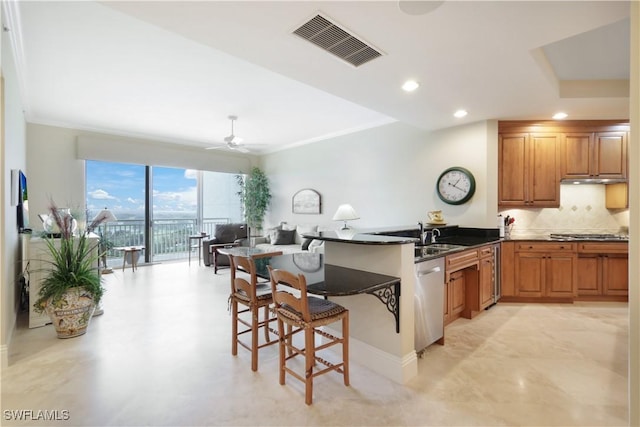 kitchen featuring appliances with stainless steel finishes, a breakfast bar, dark stone countertops, decorative backsplash, and kitchen peninsula