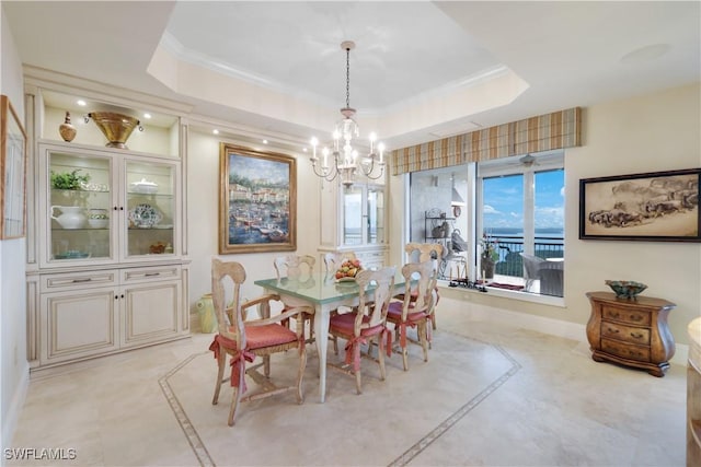 dining space with crown molding, a tray ceiling, and a chandelier