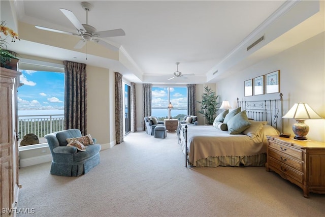 carpeted bedroom with crown molding, a raised ceiling, and a water view