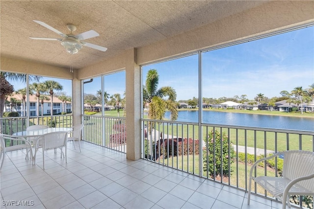 unfurnished sunroom with ceiling fan and a water view