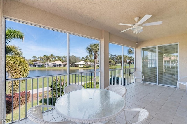 sunroom / solarium with a water view and ceiling fan