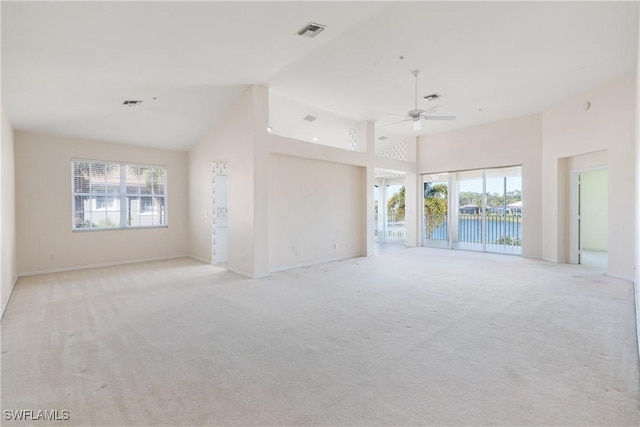 unfurnished living room featuring light colored carpet, a healthy amount of sunlight, and a water view