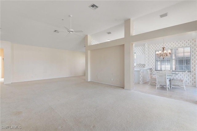 unfurnished living room featuring ceiling fan with notable chandelier, wallpapered walls, visible vents, and light colored carpet