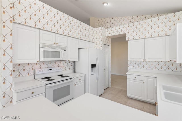 kitchen with white appliances, wallpapered walls, white cabinets, light countertops, and light tile patterned flooring