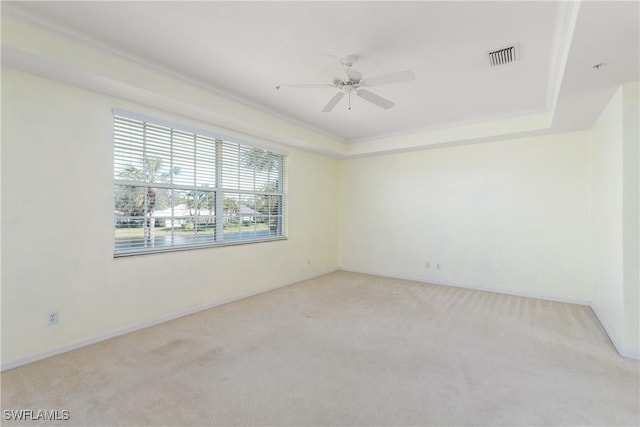 spare room featuring a tray ceiling, light colored carpet, and ceiling fan