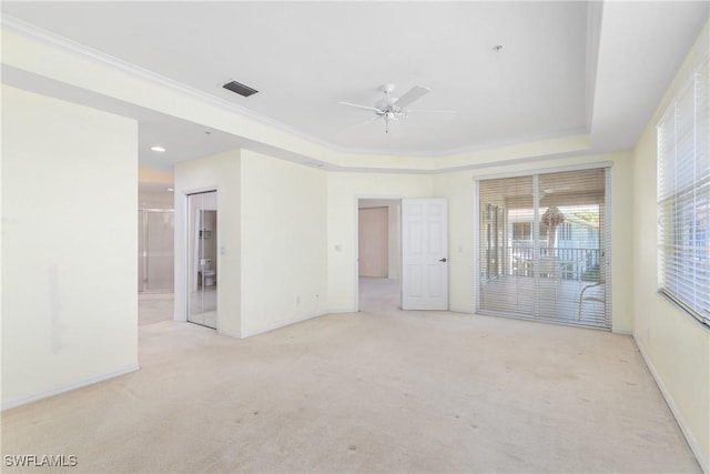 carpeted spare room with crown molding, ceiling fan, and a raised ceiling