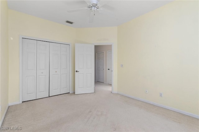 unfurnished bedroom featuring ceiling fan, light colored carpet, visible vents, baseboards, and a closet