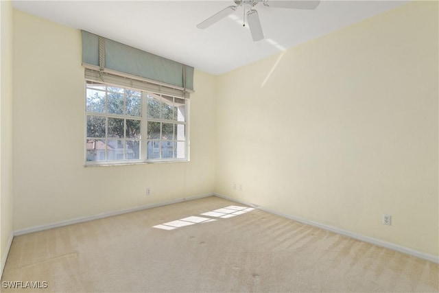 carpeted spare room with a ceiling fan and baseboards