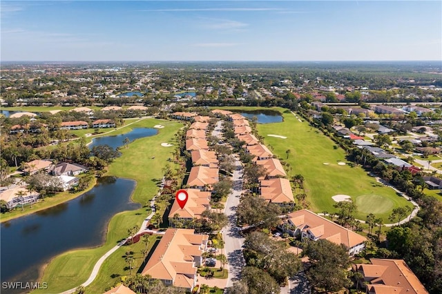 drone / aerial view featuring golf course view, a water view, and a residential view