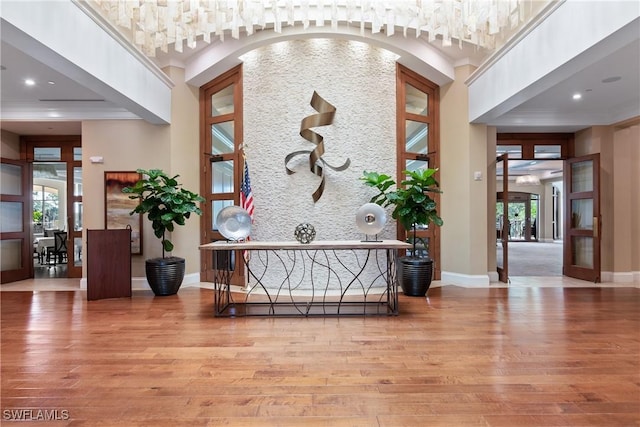 foyer featuring french doors, a towering ceiling, and light hardwood / wood-style flooring