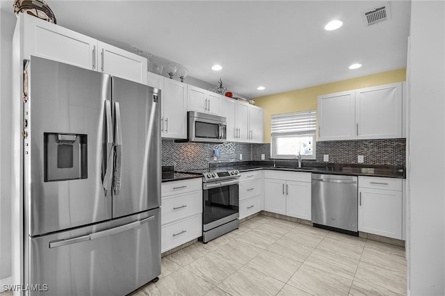 kitchen featuring stainless steel appliances, white cabinetry, sink, and tasteful backsplash