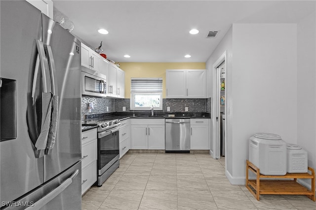 kitchen with sink, stainless steel appliances, decorative backsplash, and white cabinetry