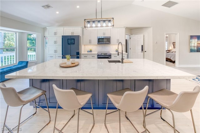 kitchen featuring appliances with stainless steel finishes, a sink, lofted ceiling, a large island, and white cabinets