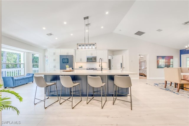 kitchen with a kitchen breakfast bar, a spacious island, appliances with stainless steel finishes, decorative light fixtures, and white cabinetry