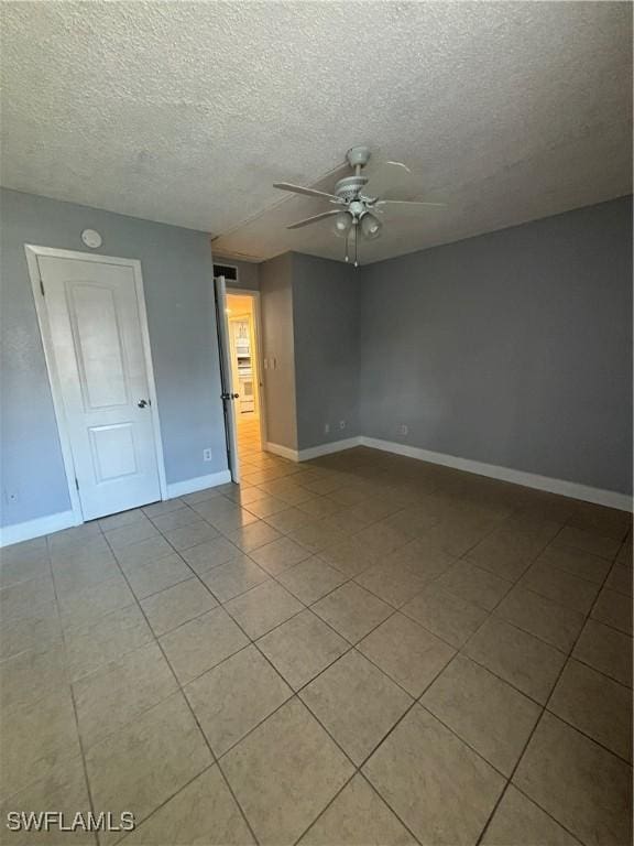 tiled empty room featuring ceiling fan and a textured ceiling