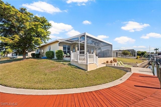 rear view of house with a water view, a yard, and glass enclosure