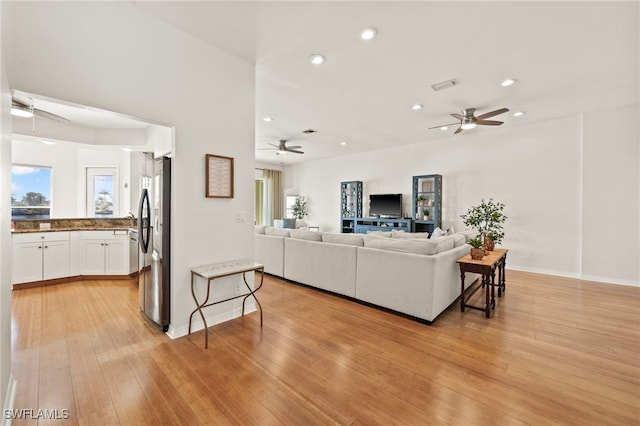 living room featuring ceiling fan, light hardwood / wood-style flooring, and a healthy amount of sunlight