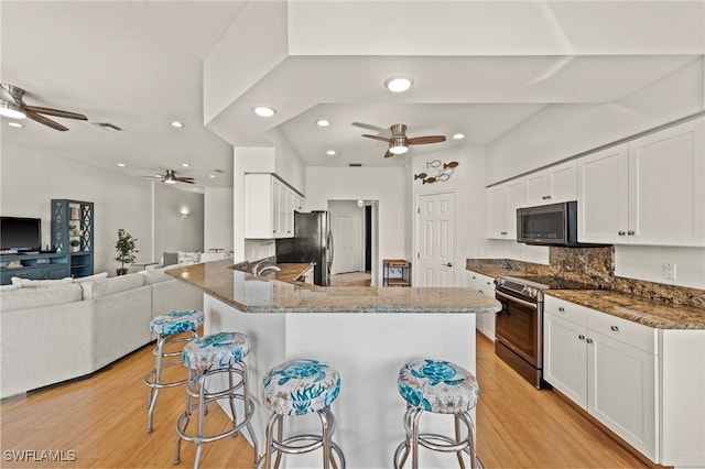 kitchen featuring stainless steel appliances, white cabinetry, a kitchen breakfast bar, and kitchen peninsula