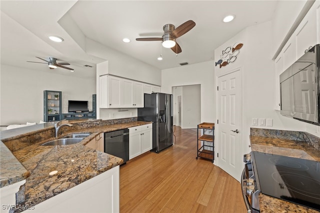 kitchen featuring sink, white cabinetry, stainless steel appliances, kitchen peninsula, and dark stone counters