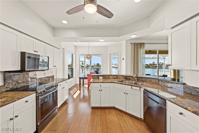 kitchen with dark stone countertops, sink, stainless steel appliances, and white cabinets