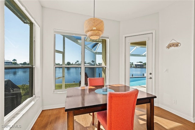 dining space featuring hardwood / wood-style flooring and a water view