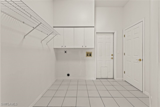 washroom with cabinets, a high ceiling, light tile patterned floors, hookup for a washing machine, and hookup for an electric dryer