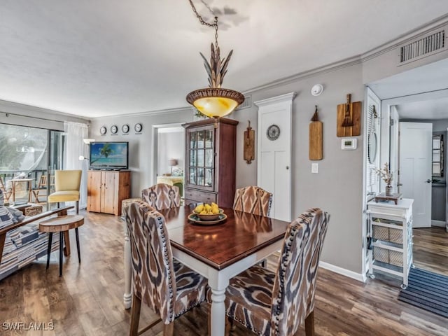 dining space featuring ornamental molding and dark wood-type flooring