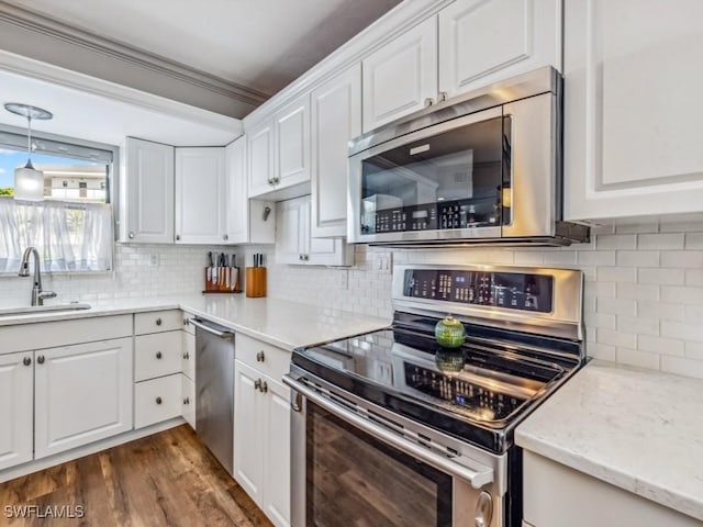 kitchen with sink, stainless steel appliances, tasteful backsplash, decorative light fixtures, and white cabinets