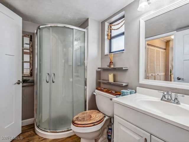 bathroom with hardwood / wood-style floors, vanity, toilet, and a shower with shower door