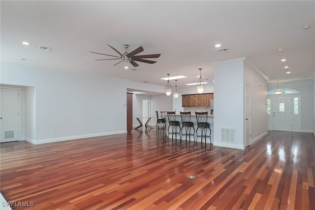 unfurnished living room featuring dark hardwood / wood-style floors, ceiling fan, and ornamental molding