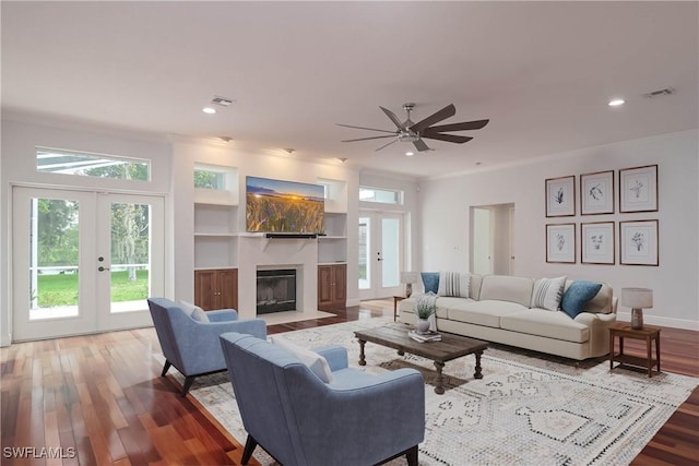 living room with french doors, built in features, ceiling fan, and wood-type flooring