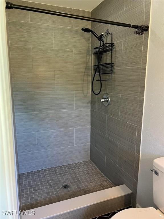 bathroom featuring a tile shower and toilet