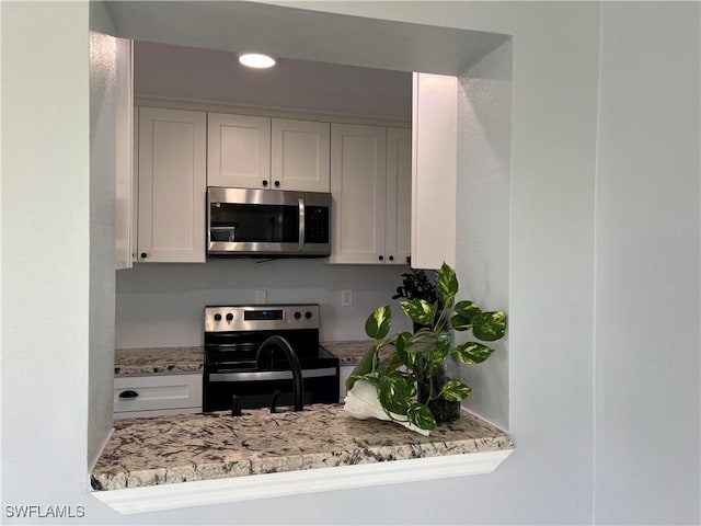 kitchen featuring light stone counters, stainless steel appliances, sink, and white cabinets