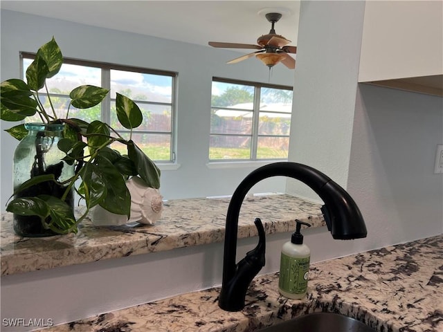 interior details with light stone countertops and ceiling fan