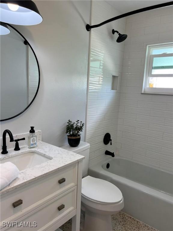 full bathroom with vanity, tiled shower / bath, and toilet